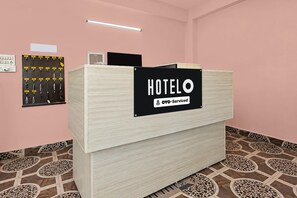 A hotel reception desk with a sign indicating it is serviced by OYO.