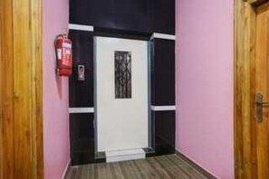 A hallway with a door, a fire extinguisher, and a small step leading to the door.