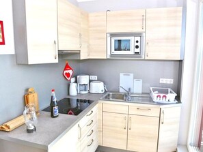 A compact kitchen with a microwave, toaster, and sink. - Ferienwohnung in Fehmarn-burgtiefe (Fehmarn)