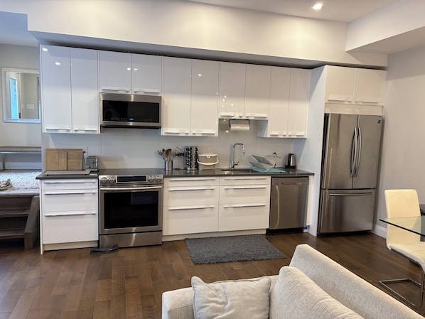 Una cocina moderna con armarios blancos, electrodomésticos de acero inoxidable y una alfombra gris.