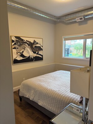 Ein Schlafzimmer mit einem Bett, einem Fenster, einer Heizung und einem Bild an der Wand.