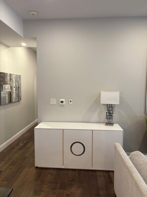 Una sala de estar moderna con un mueble blanco, una lámpara y un cuadro en la pared.