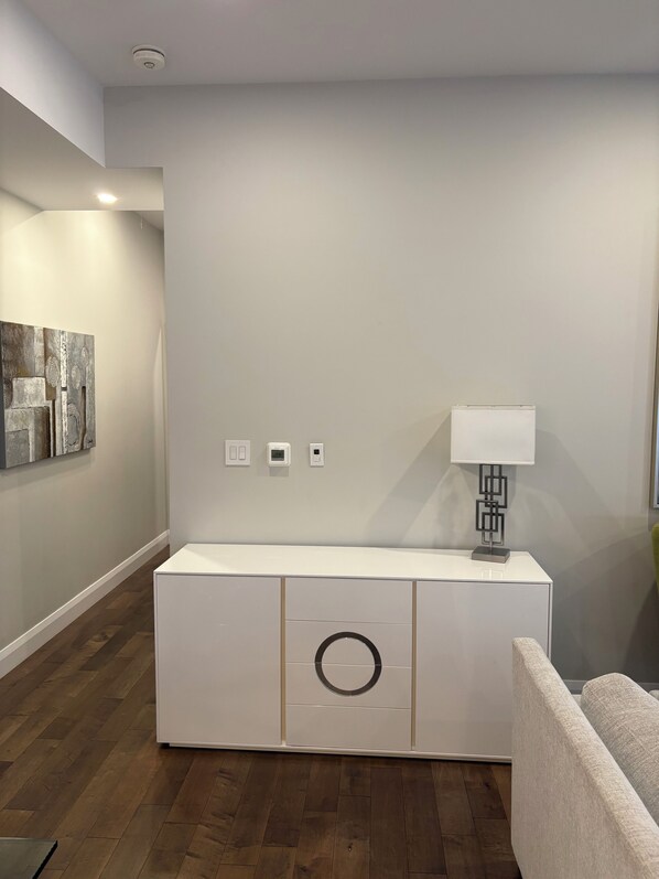 A modern living room with a white cabinet, a lamp, and a painting on the wall.