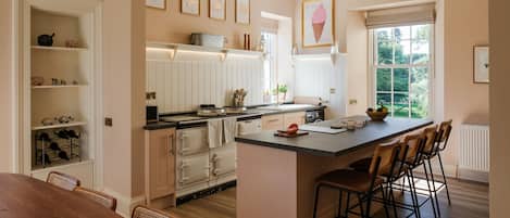 A kitchen with a central island, wooden chairs, a dining table, and a window with a view.