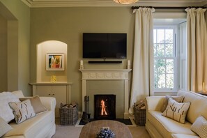 A living room with a fireplace, two sofas, a television, and a window with curtains. - Isla Farmhouse - Luxury Cottages (Perth)