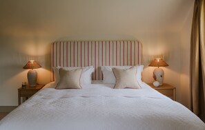 Ein Hotelzimmer mit einem großen Bett, zwei Nachttischen und einem gestreiften Kopfteil.