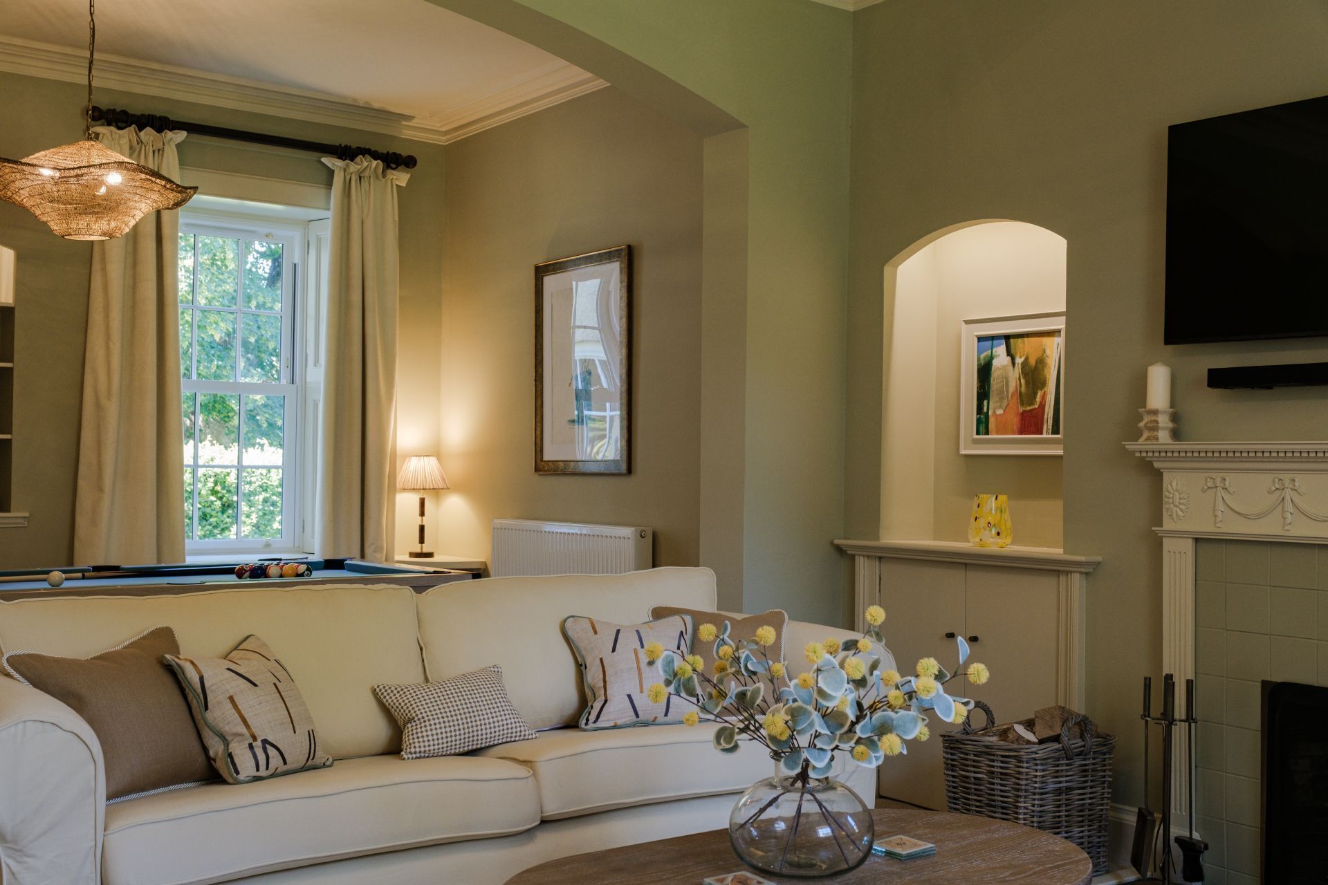 A living room with a sofa, a coffee table, a fireplace, and a television mounted on the wall.