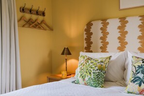 A hotel room with a bed, a nightstand, a lamp, and a wall-mounted coat rack. - Isla Farmhouse - Luxury Cottages (Perth)