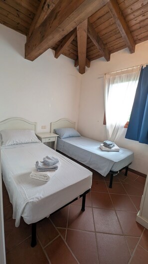 A room with two beds, a window with curtains, and a wooden ceiling. - Villa Liliana: Your Private Oasis with a Pool (Stintino)