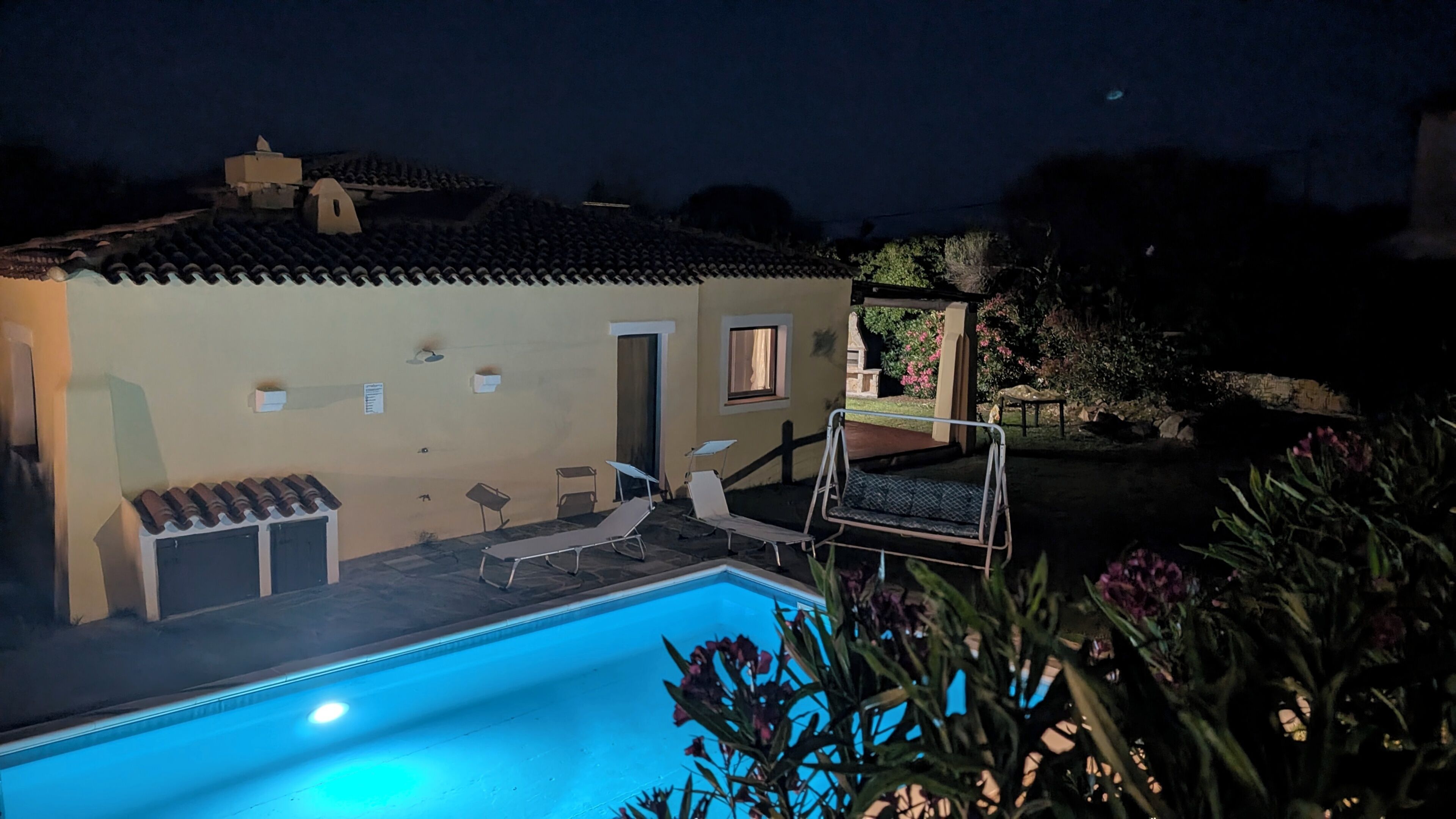 A residential property with a swimming pool, outdoor seating, and a garden.