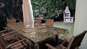 An outdoor patio with a table covered in a fruit pattern tablecloth, surrounded by wooden chairs. - Villa Liliana: Your Private Oasis with a Pool (Stintino)