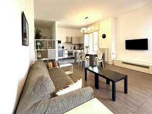 A modern living room with a sofa, a dining table, and a kitchen in the background. - Fritz Three-room apartment kitchen+terraces, Virgilio spa area, 5 minutes from Bremen beach (Sirmione)