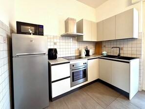 A compact kitchen with a refrigerator, oven, microwave, and a sink. - Fritz Three-room apartment kitchen+terraces, Virgilio spa area, 5 minutes from Bremen beach (Sirmione)