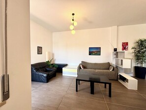 A modern living room with a sofa, a coffee table, and a bookshelf. - Fritz Three-room apartment kitchen+terraces, Virgilio spa area, 5 minutes from Bremen beach (Sirmione)