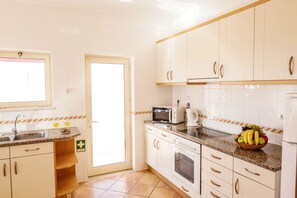 A kitchen with white cabinets, a microwave, a kettle, and a fruit bowl on the counter. - Villa w/ heatable pool & sea view in Galé (Albufeira)
