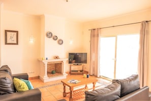 A living room with a fireplace, a television, and a sofa. - Villa w/ heatable pool & sea view in Galé (Albufeira)