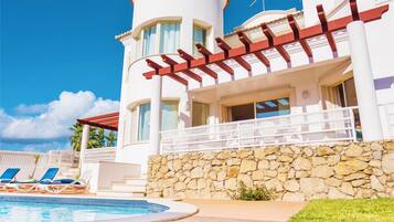 A resort with a swimming pool, lounge chairs, and a stone wall.