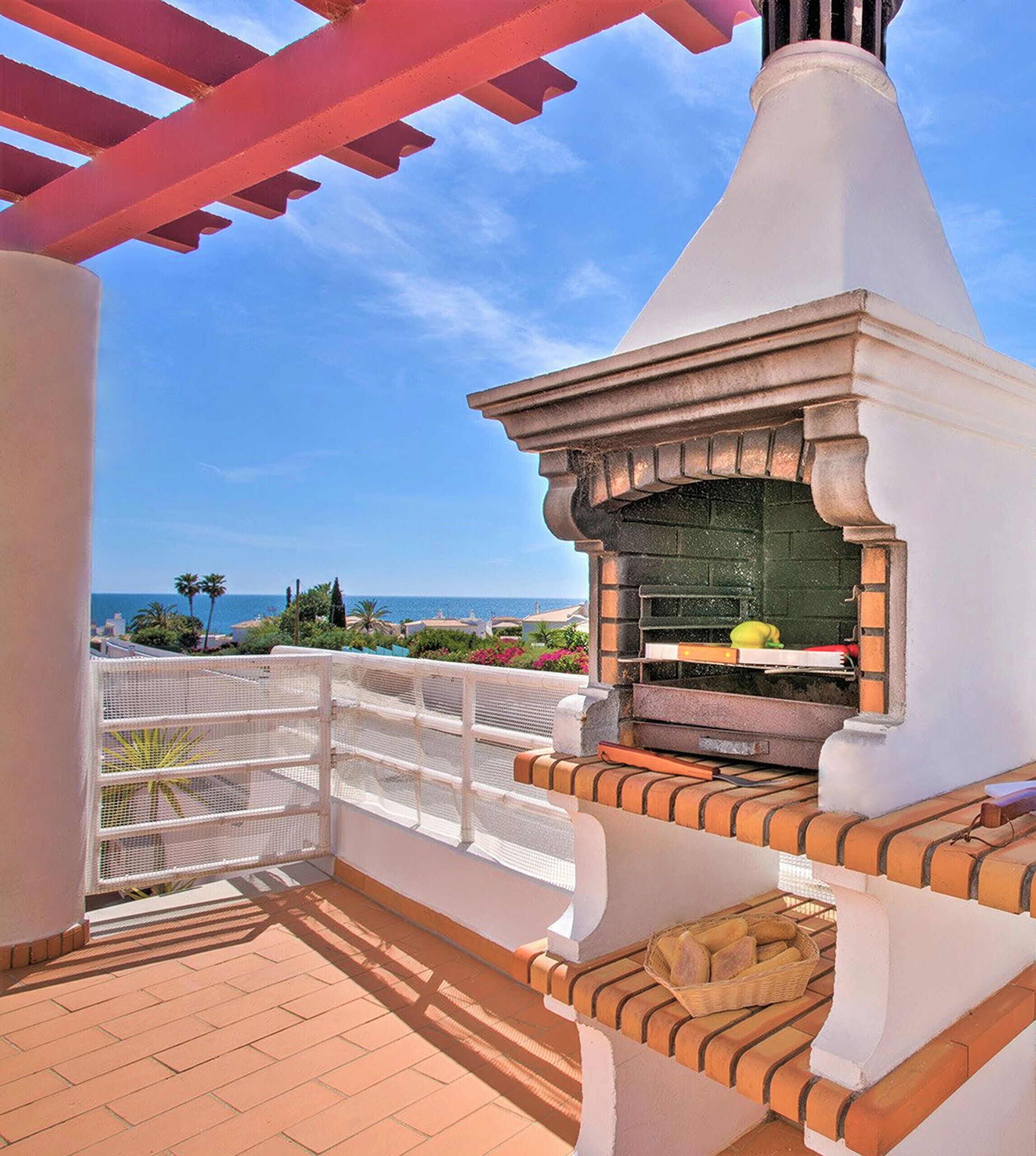 An outdoor patio with a brick oven and a white railing.