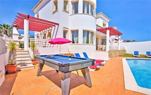 Ein Poolbereich mit Billardtisch, Liegestühlen und einem Pool.