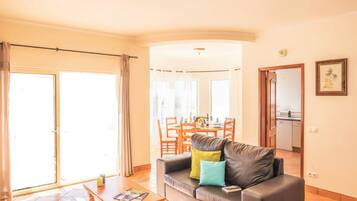 A living room with a sofa, coffee table, and a dining area with chairs and a table.