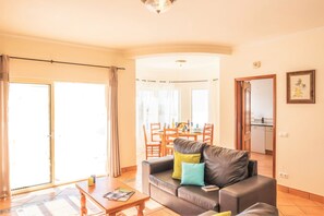 Ein Wohnzimmer mit Sofa, Couchtisch und einem Essbereich mit Stühlen und Tisch.