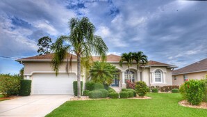 A two-story house with a garage, a well-maintained lawn, and a variety of shrubs and trees. - Perfect 4-bedroom house with heated pool in Rotonda West for large families! (Rotonda West)