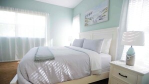 A bedroom with a bed, a nightstand, a lamp, and a painting on the wall. - Perfect 4-bedroom house with heated pool in Rotonda West for large families! (Rotonda West)