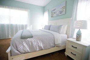A bedroom with a bed, a nightstand, a lamp, and a painting on the wall. - Perfect 4-bedroom house with heated pool in Rotonda West for large families! (Rotonda West)