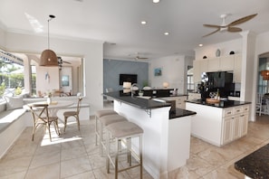 A modern kitchen with a central island, bar stools, and a dining area with a view. - Perfect 4-bedroom house with heated pool in Rotonda West for large families! (Rotonda West)