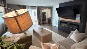 A modern living room with a sofa, a coffee table, a lamp, and a flat-screen TV.
