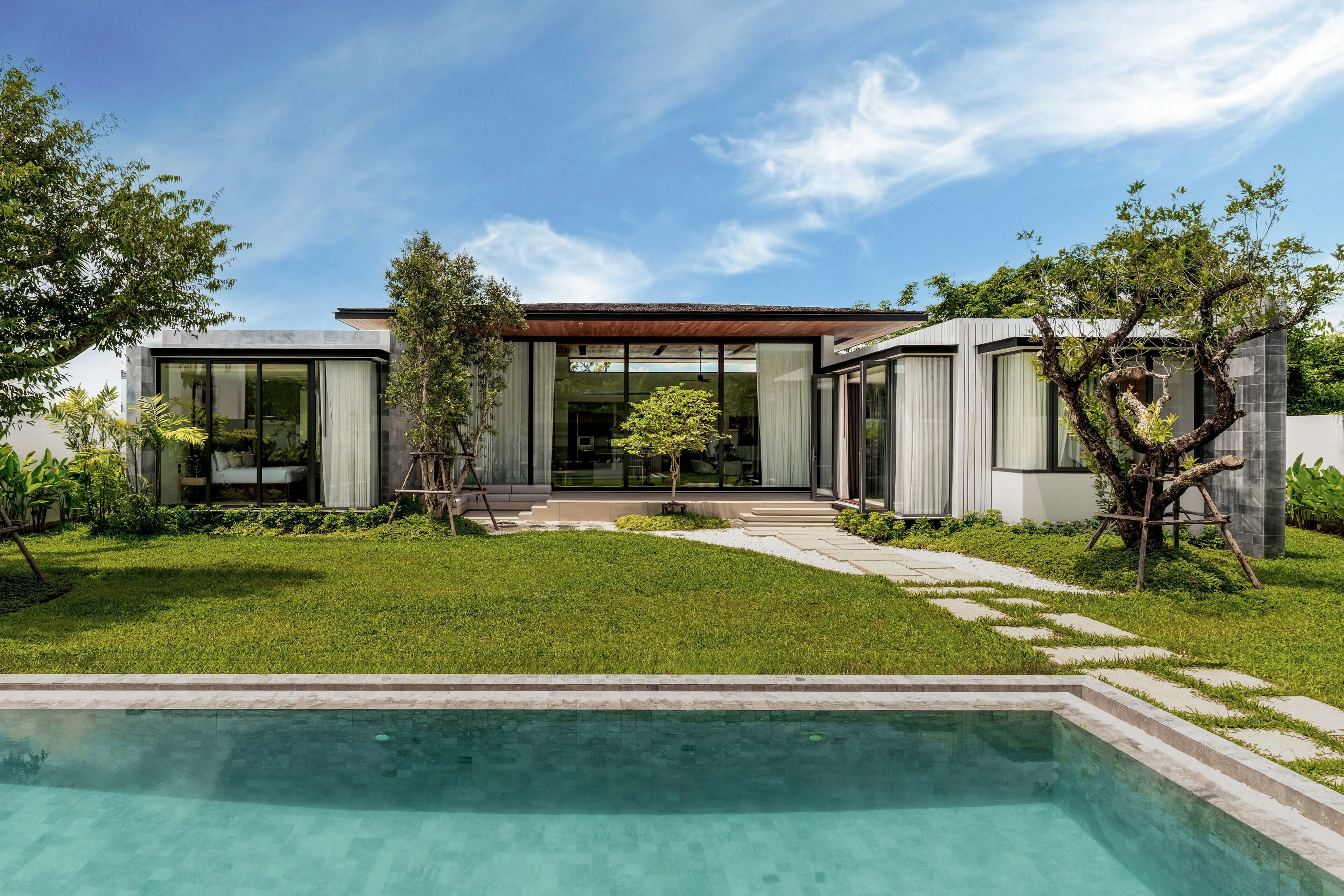 Et moderne hus med swimmingpool, have og en blå himmel.