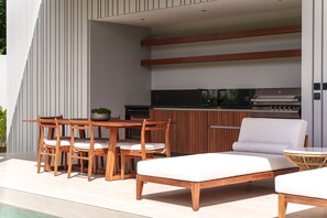 An outdoor kitchen area with a grill, dining table, and chairs. - Botanica Foresta Luxury 4BR Villa • Private Pool (Thep Krasatti)
