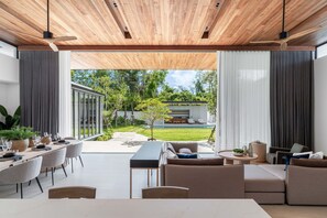 Ein modernes Interieur mit Essbereich, Sofas und Blick auf Garten und Pool.