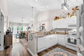 A modern kitchen with white cabinetry, a central island, and a view to the living area. - 2 bed 2 bath condo in Ocean Keyes, N. Myrtle Beach (North Myrtle Beach)