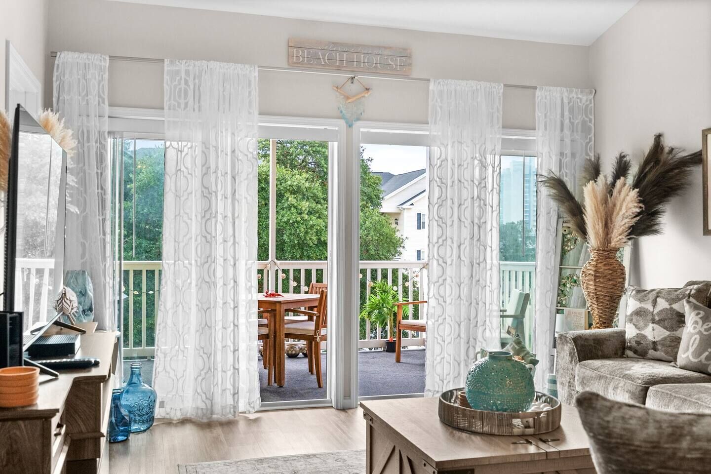 A living room with a view of a balcony, a wooden table, and a sofa.