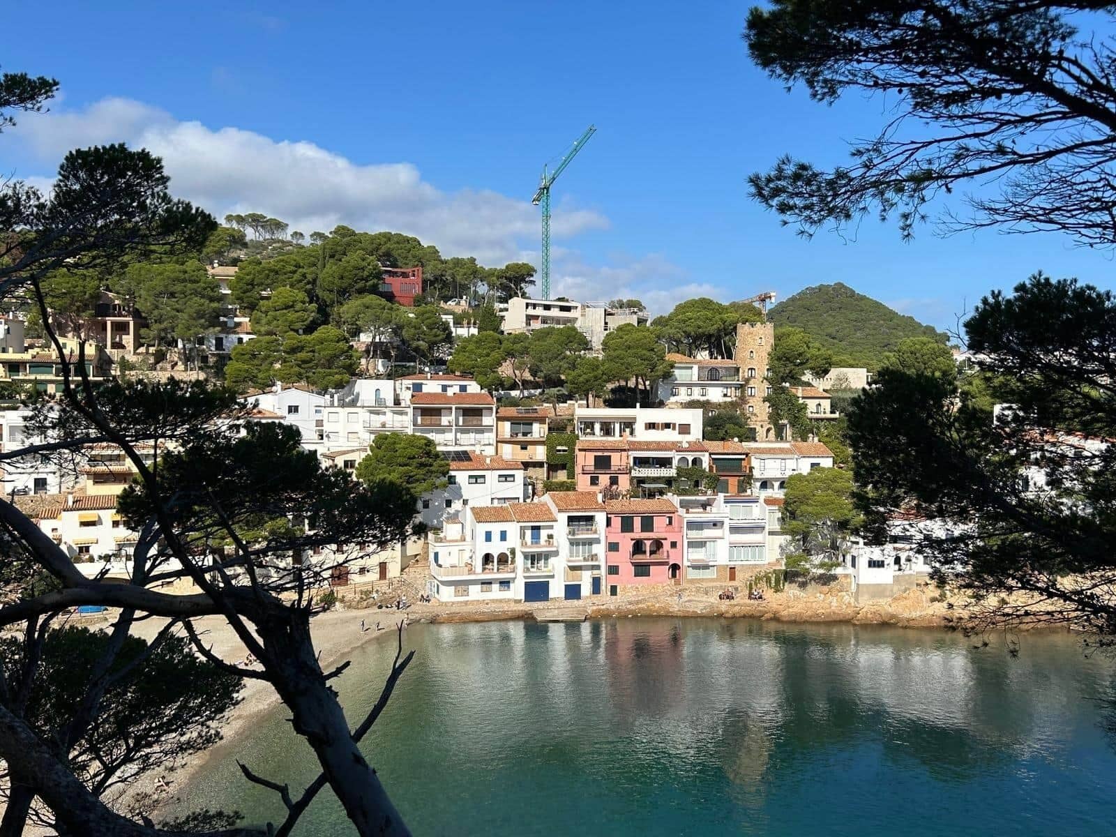 A coastal town with buildings along the waterfront, a clear sky, and a construction crane in the distance.