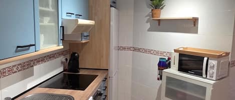 Una cocina compacta con lavavajillas integrado, microondas y estufa.