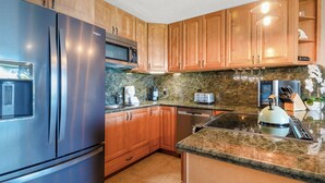Eine moderne Küche mit Edelstahlgeräten, Holzschränken und Granit Arbeitsplatten, inklusive eingebautem Backofen.