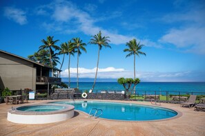 A pool area with a hot tub, lounge chairs, and a view of the ocean. - Polynesian Shores 114 by Gather - Oceanfront 1BR w/ Pool & Ocean Views (Lahaina)