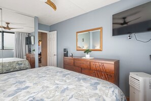 A bedroom with a bed, dresser, mirror, and a ceiling fan. - Polynesian Shores 114 by Gather - Oceanfront 1BR w/ Pool & Ocean Views (Lahaina)