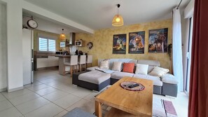 A modern living room with a sofa, a wooden coffee table, and a kitchen area with a dining set. - Charming house with an enclosed garden and a patio between Chartres and Rambouillet (Auneau)