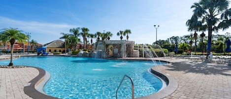 Una piscina con una fuente, rodeada de palmeras y sillas de descanso.