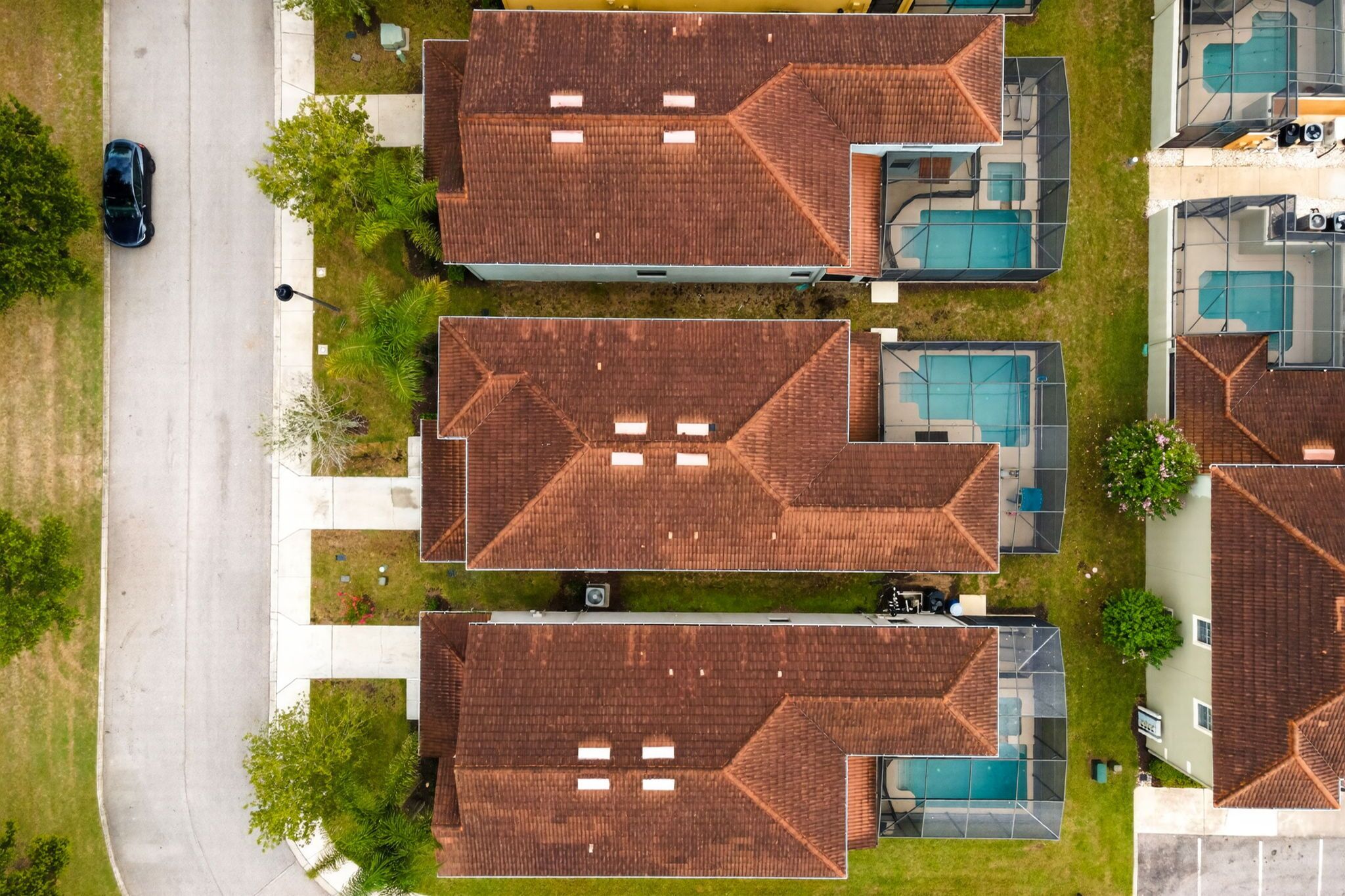 Een woongebied met drie huizen, elk voorzien van een zwembad en een garage.