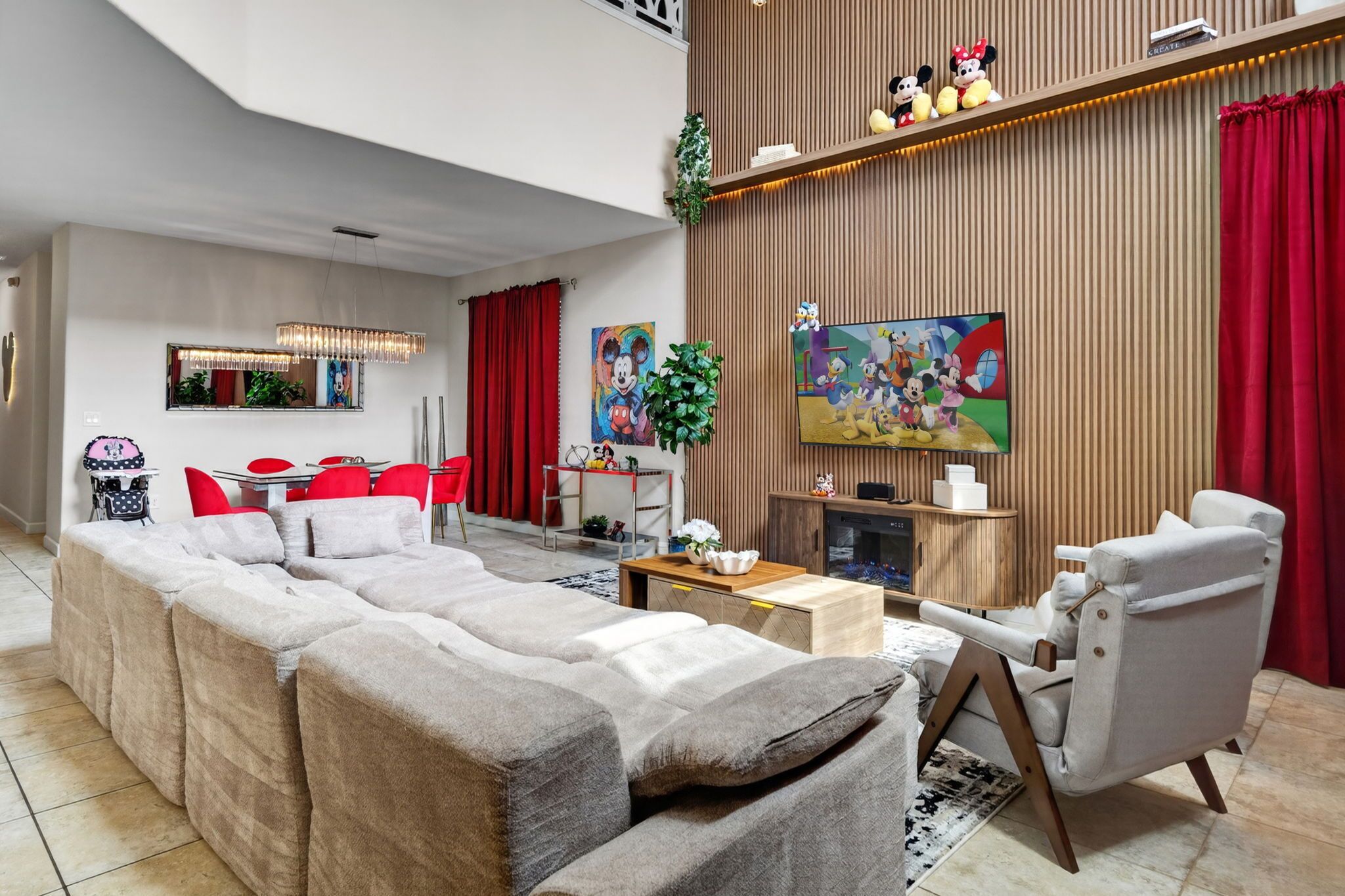 Un salon moderne avec un grand canapé d’angle, un téléviseur à écran plat et un rideau rouge.