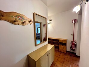 A hallway with a wooden cabinet, a mirror, a fire extinguisher, and a bench. - Central Dolomites Atelier - 3 bedrooms - apartment with mountain view (Campitello di Fassa)
