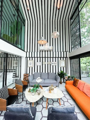 A modern living room with a striped wall, a grey sofa, an orange sofa, and a coffee table with decorative items.