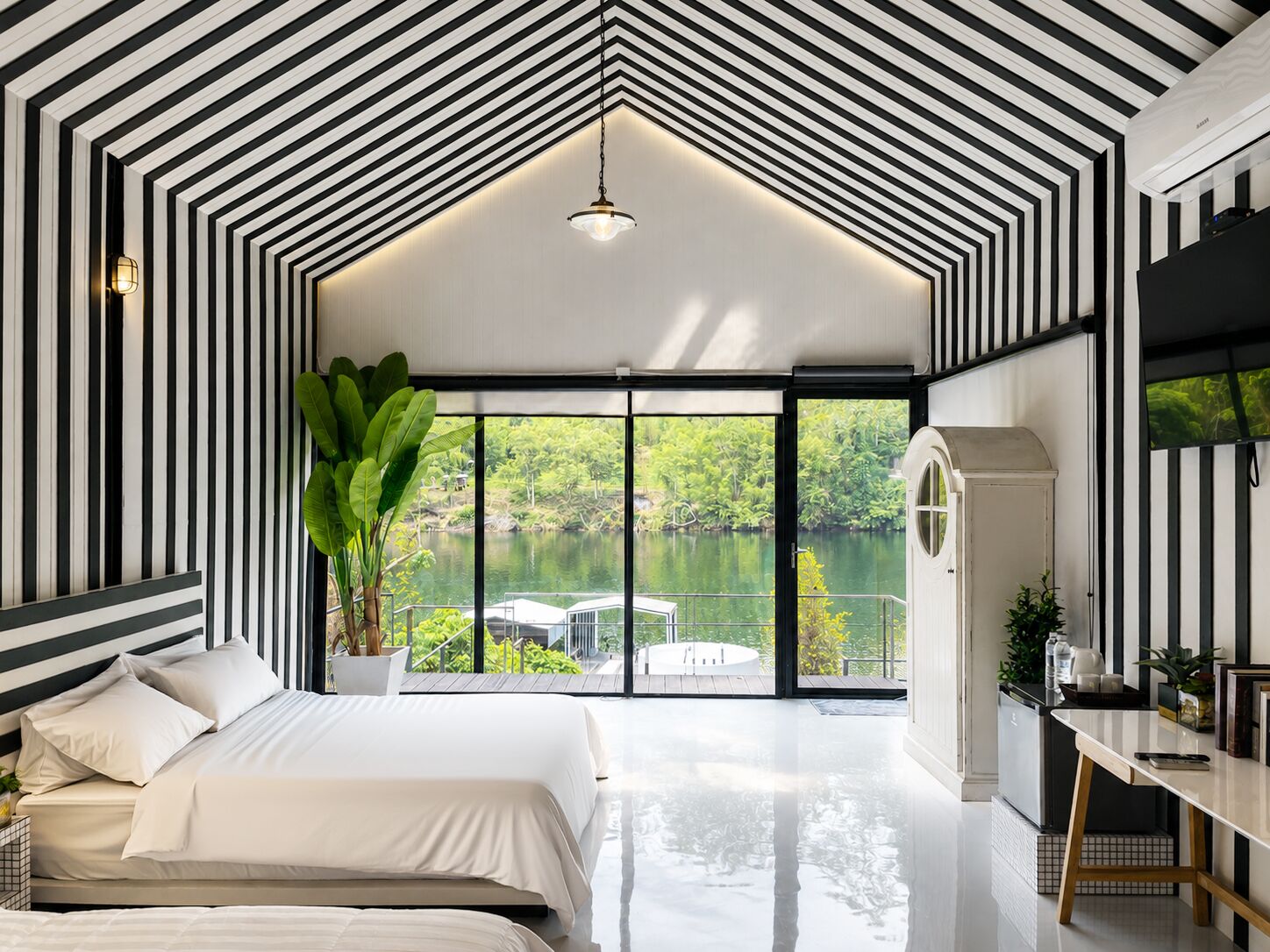 Une chambre moderne avec un grand lit, un bureau et une vue sur un lac.