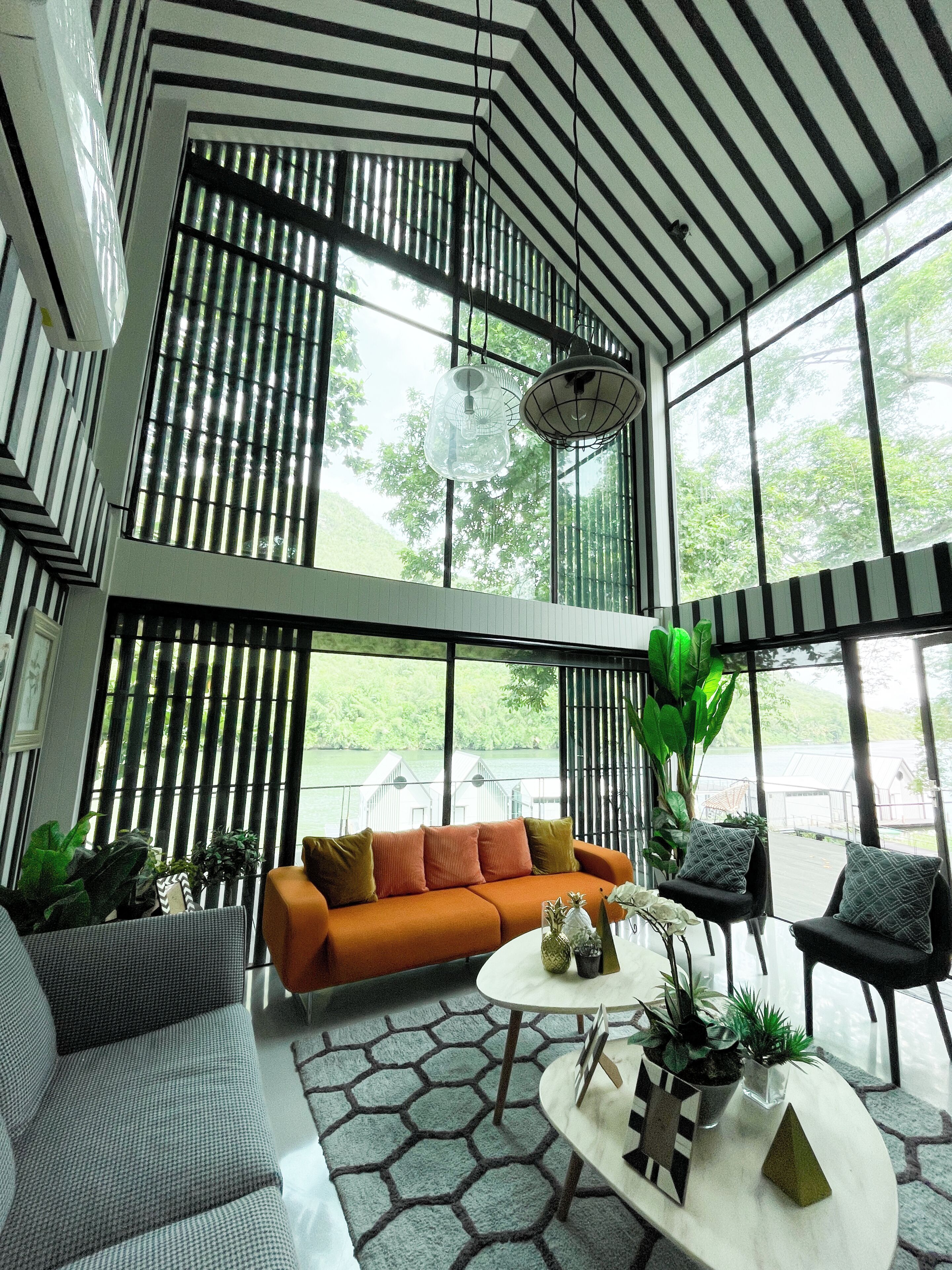 A spacious interior with a high ceiling, large windows, and a modern sofa set.