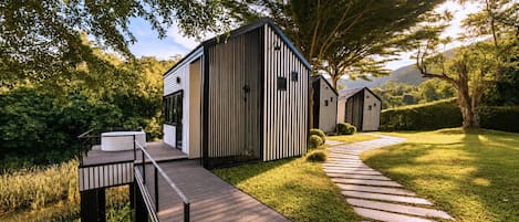 A modern outdoor structure with a wooden deck and a pathway leading to it.