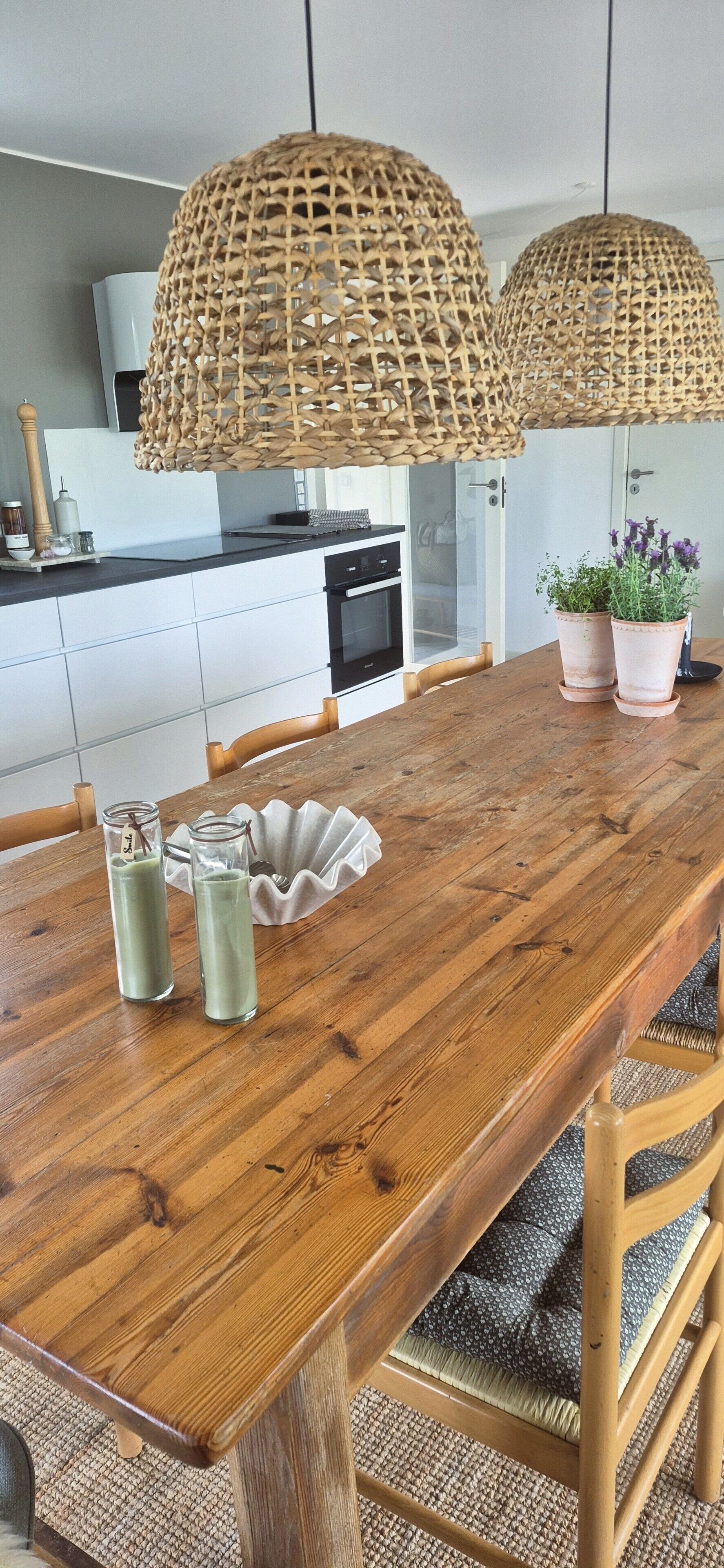 Ein Holztisch mit zwei Glasflaschen, einer weißen Schüssel und einem gewebten Korb.